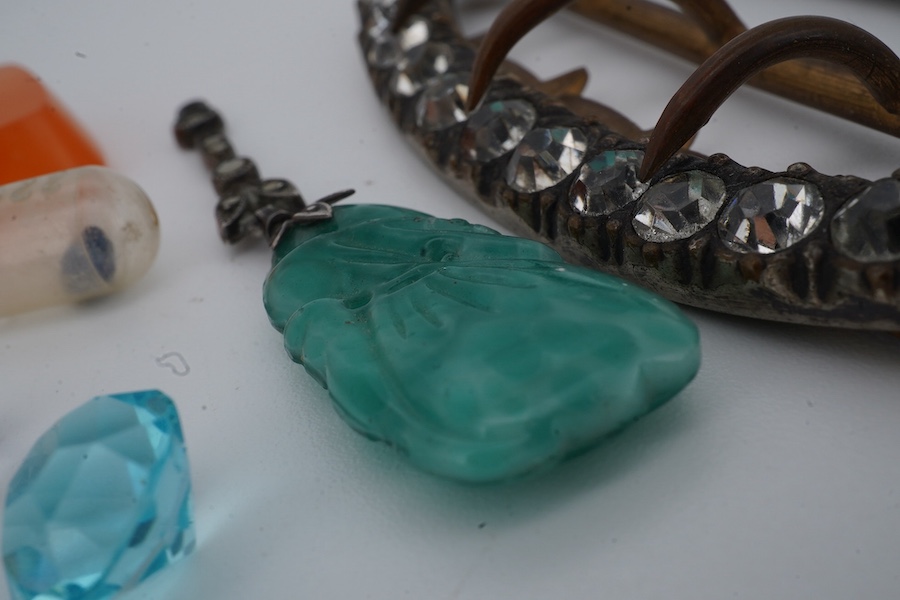 A collection of jewels and a loose sapphire, comprising: a shoe buckle set with colourless pastes, length 6.8cm; a green paste and marcasite pendant imitating jadeite; a polished slab of carnelian; a loose cushion-shaped